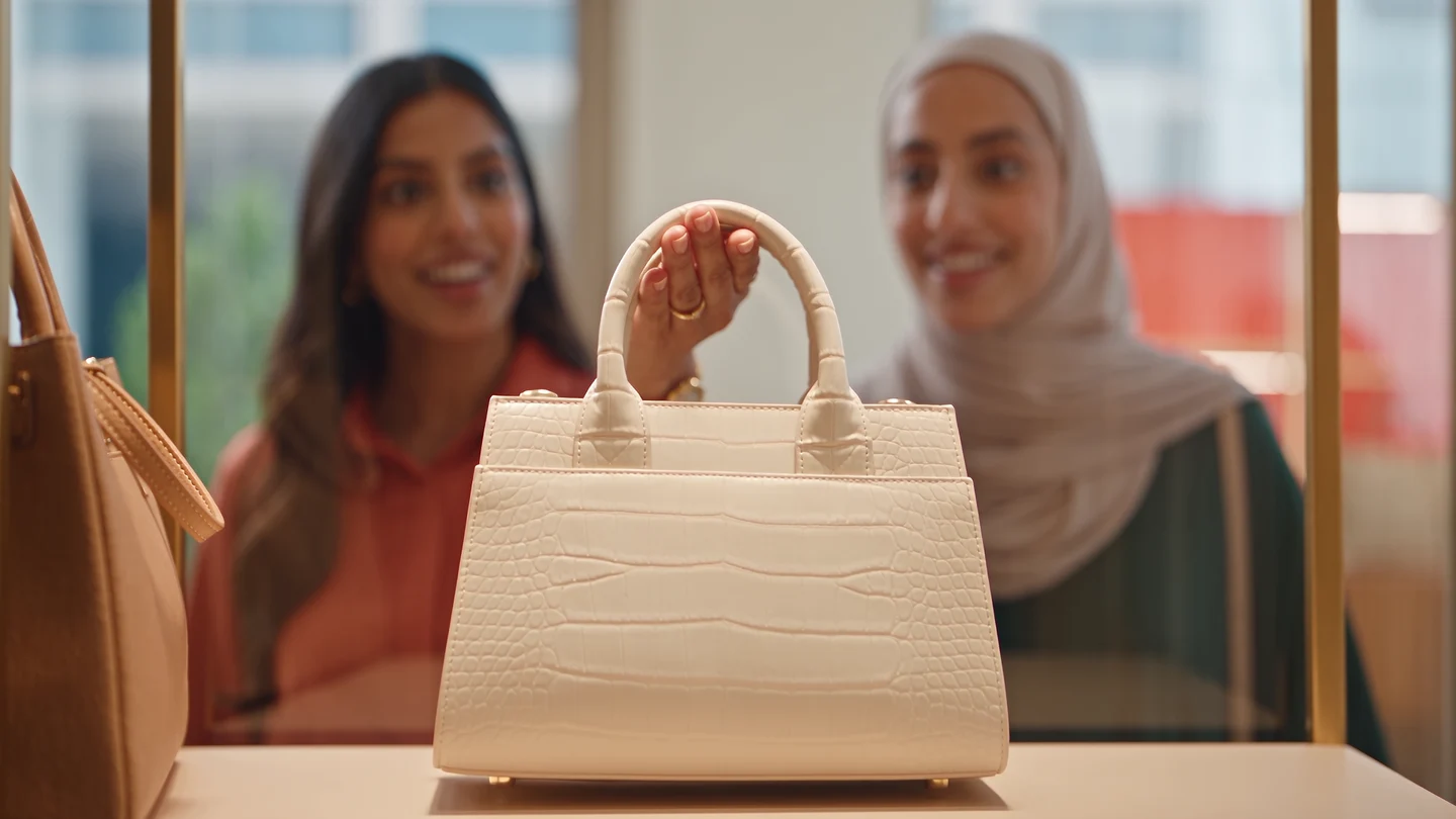 Illustrative shoppers discovering a handbag offer and using it at checkout